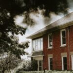 a brick building with trees and bushes