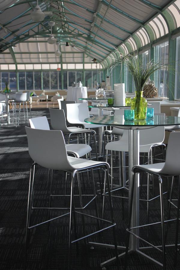 Design Inspiration 221 Elegant indoor event space featuring high-top tables, white bar stools, and modern lounge seating inside a bright glass venue.