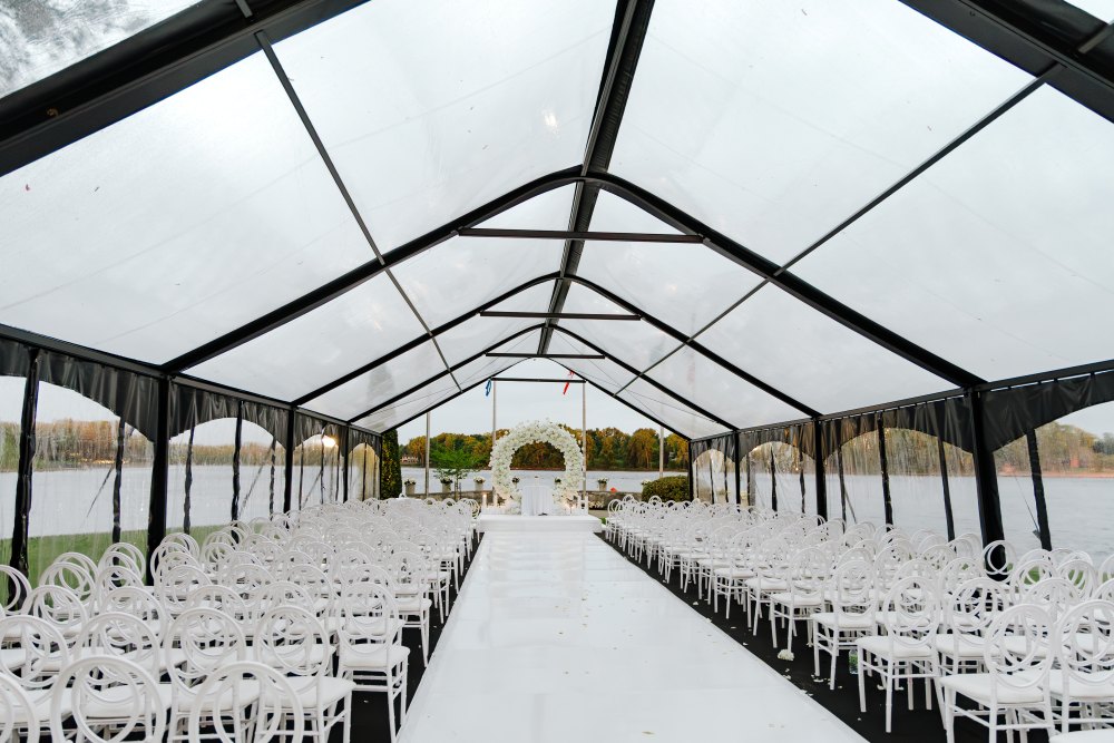 Elegant tent setup for wedding ceremony with Black Frame Clear Span Tent