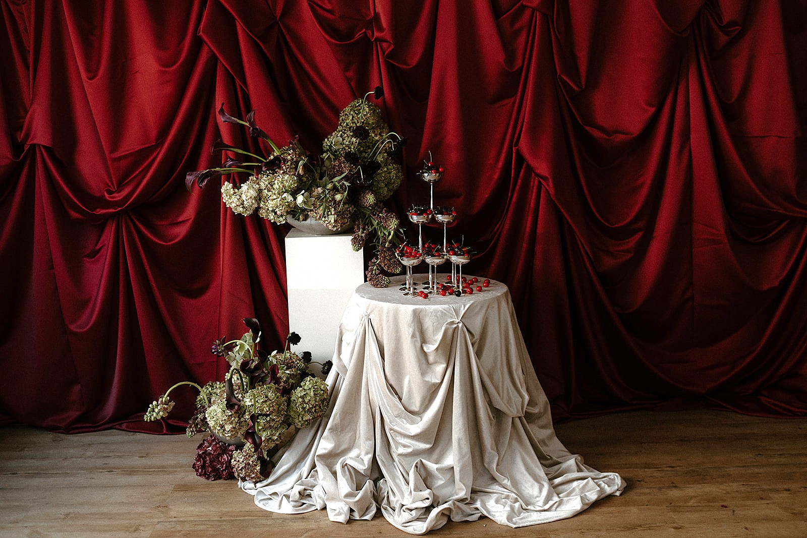 Elegant table with floral arrangements and drapery backdrops.